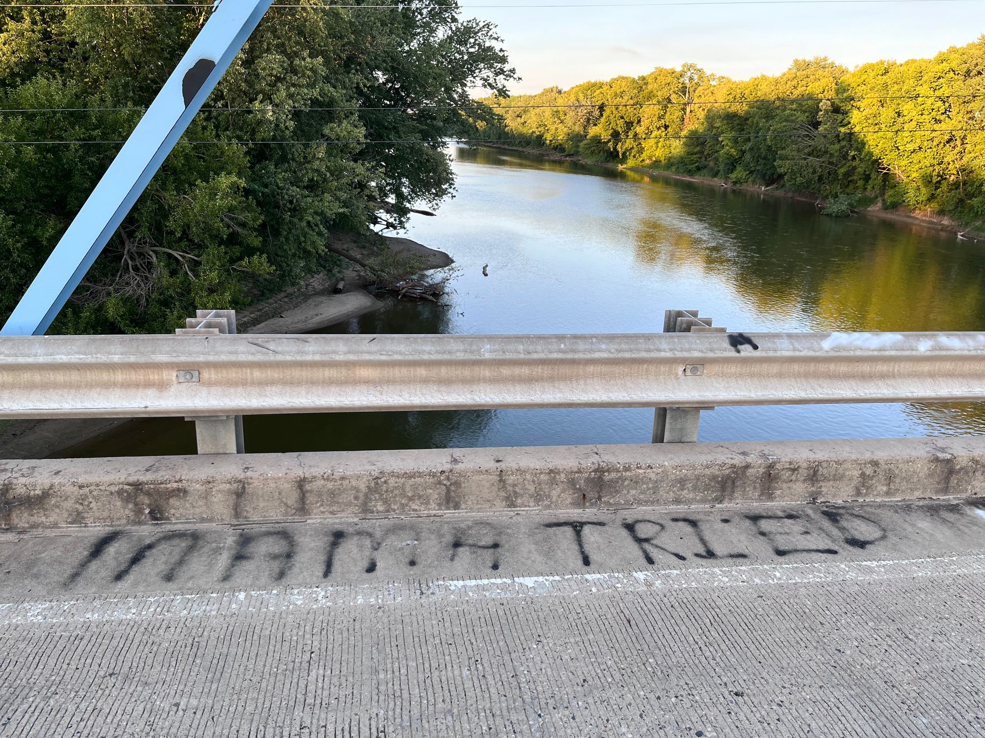 Graffiti on bridge street above river that says 'mama tried'