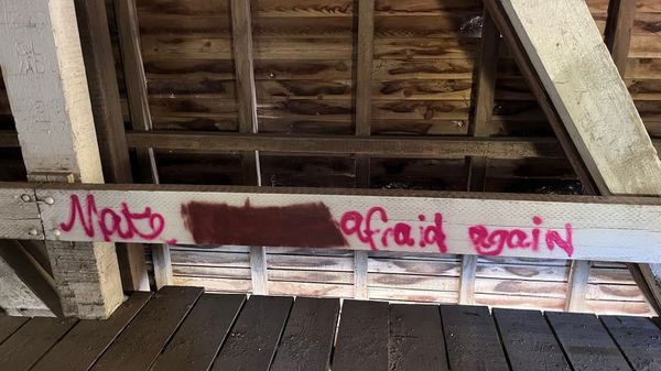 Bridge graffiti that says 'Make blank afraid again' with second word blacked out