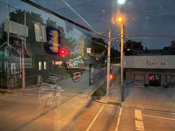 Street that shows a restaurant called Banh Mi at dusk from the second story of a bar